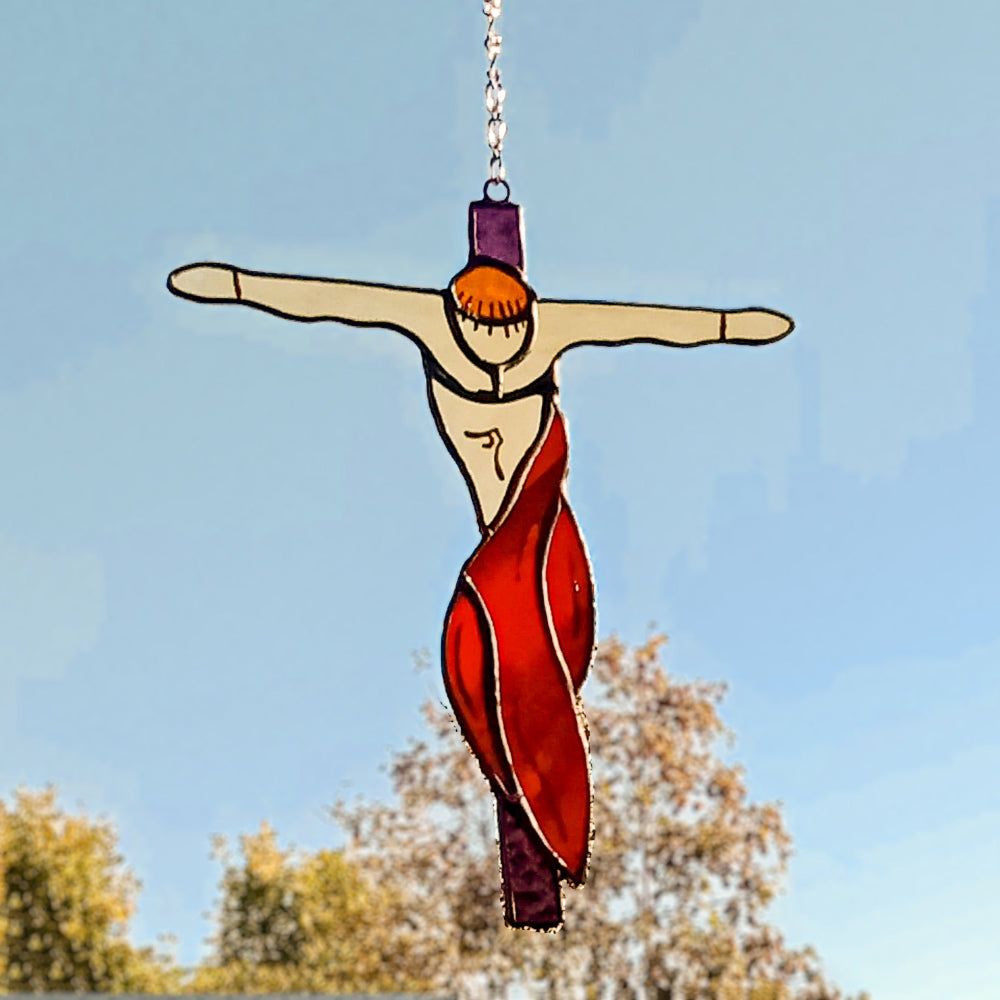 Red draped stained glass crucifixion ornament in daylight