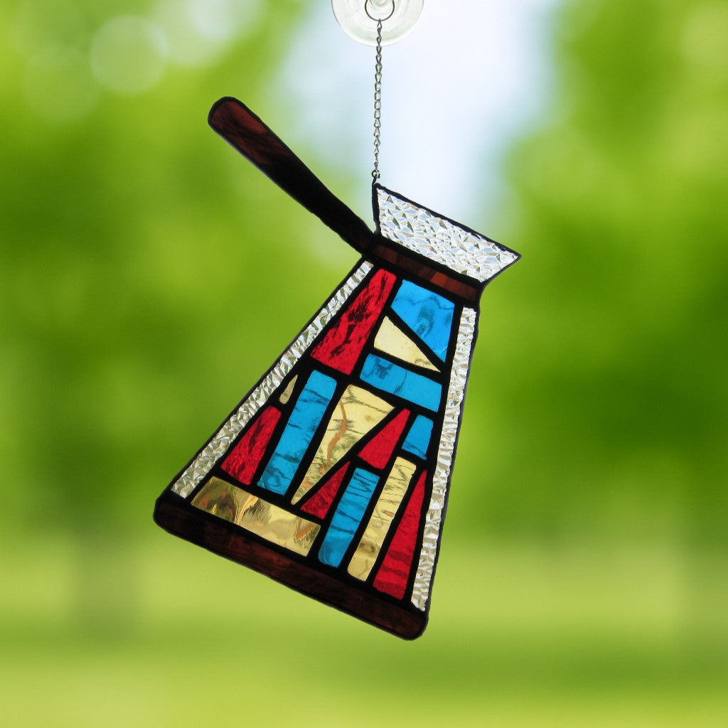 Stained glass suncatcher of a cezve coffee pot with warm brown and gold tones, handcrafted glass art for kitchen decor